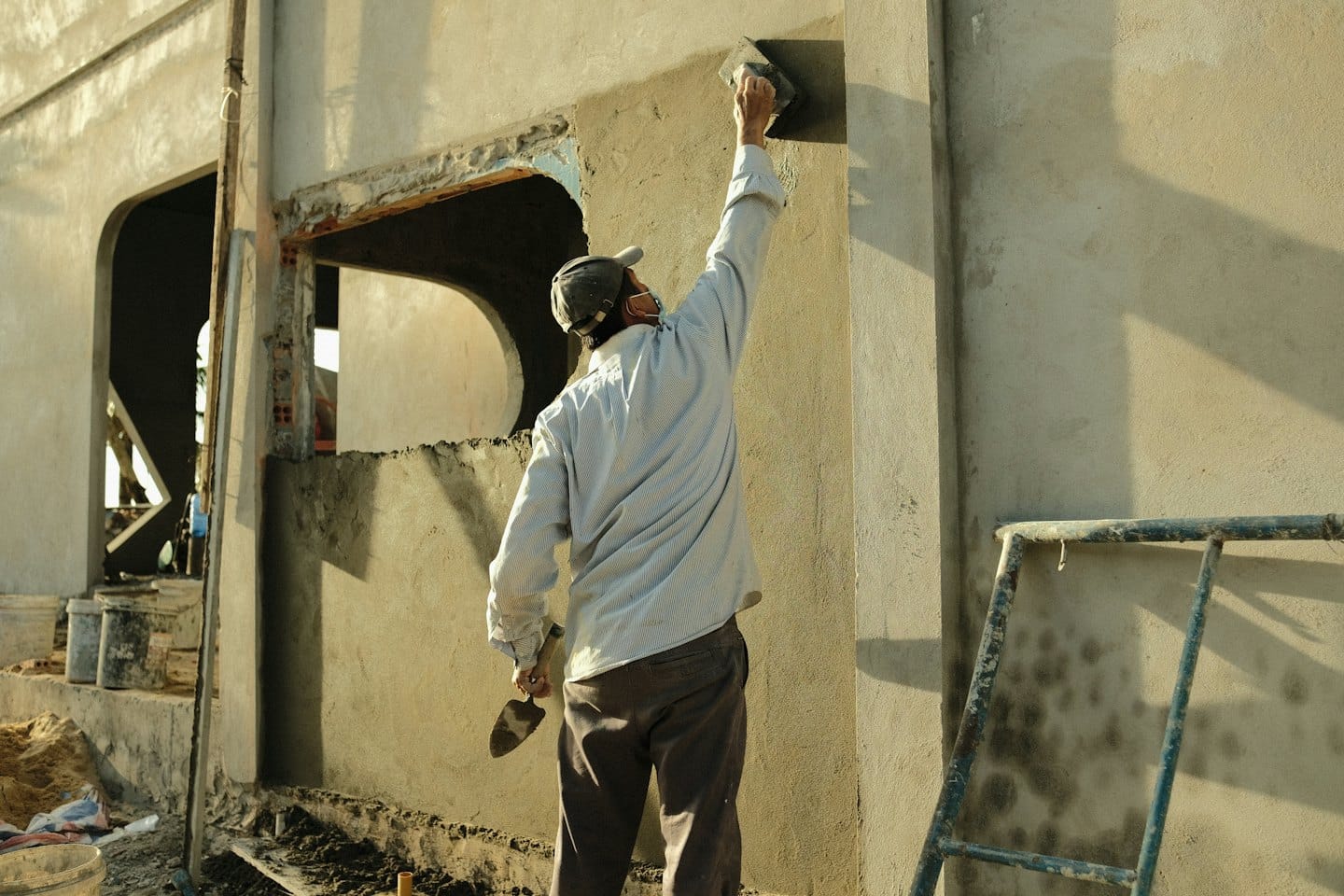 Operaio edile intonaca il muro esterno di un edificio.